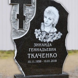 Фото надгробия в виде скалы из карельского чёрного гранита с вырезанным крестом и выбитым портретом.